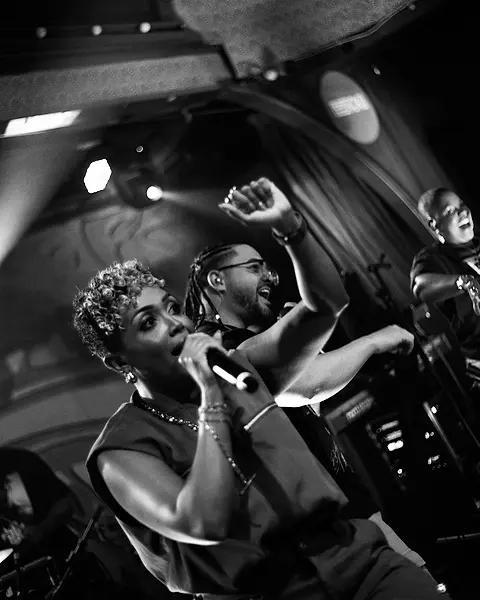 Carol e Daniel cantando juntos no palco, de punho erguido
