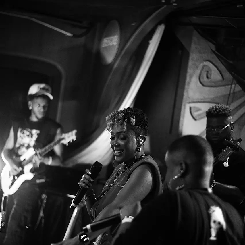 Carol cantando no palco do Black Music Live, com o guitarrista e os músicos da Black SP ao redor